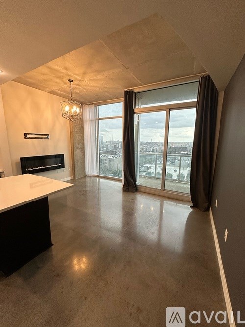 A spacious living room with a flat screen TV and large windows overlooking the city.