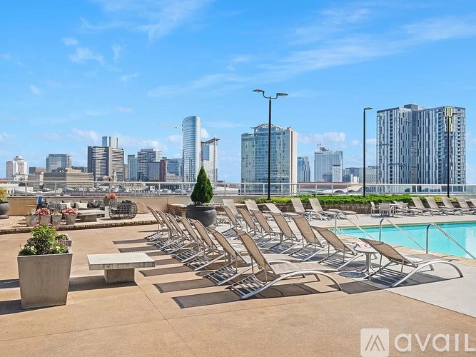 A pool area with chairs and a city skyline in the background.