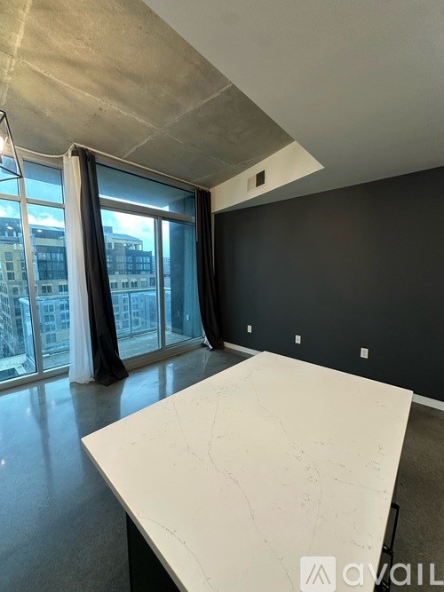 A large white table is in the center of a room with a large window and a view of a city.
