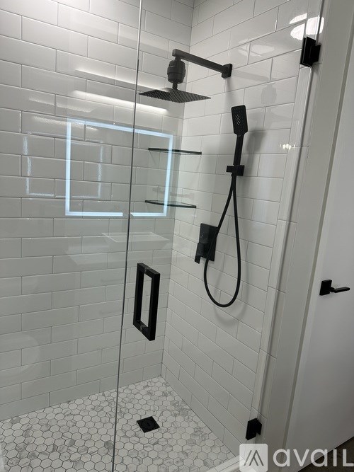 A bathroom with a glass shower door and a black handle.