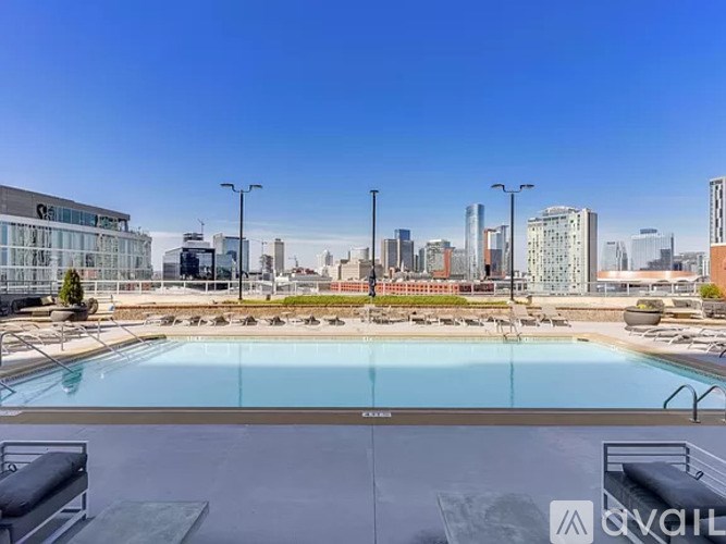 A large outdoor swimming pool with lounge chairs and a city skyline in the background.