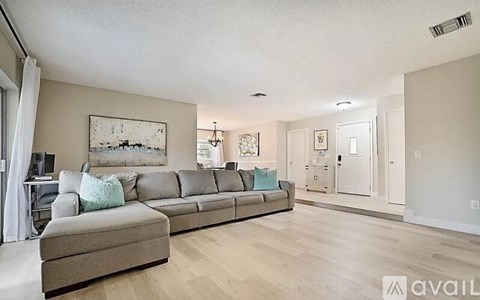 A living room with a grey couch and a painting on the wall.