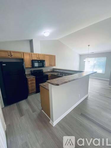 A kitchen with wooden cabinets and a black fridge.