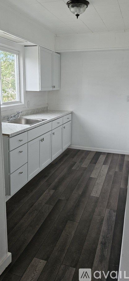 A kitchen with white cabinets and a window.