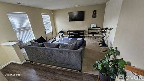 A living room with a grey couch and a television on the wall.