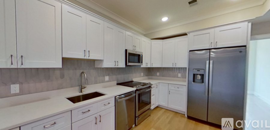 A kitchen with white cabinets and a stainless steel refrigerator.