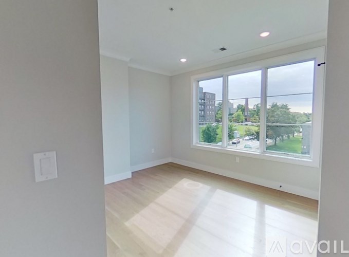 A spacious room with a large window overlooking a green landscape.