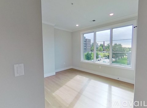 A spacious room with a large window overlooking a green landscape.