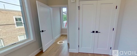 A hallway with white doors and a window overlooking a building.