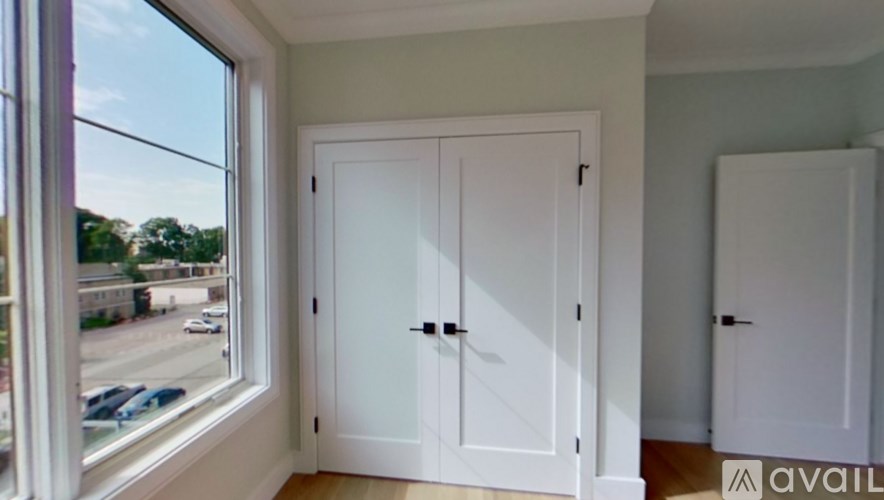 A white door with a black handle is in a room with a window.