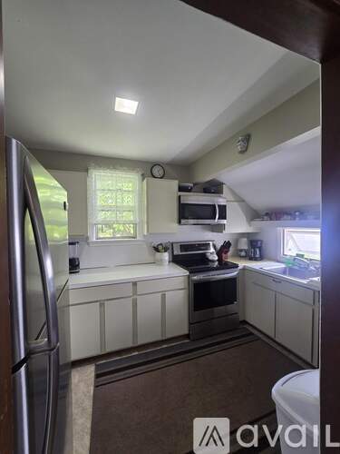 A kitchen with white cabinets and a stainless steel refrigerator.