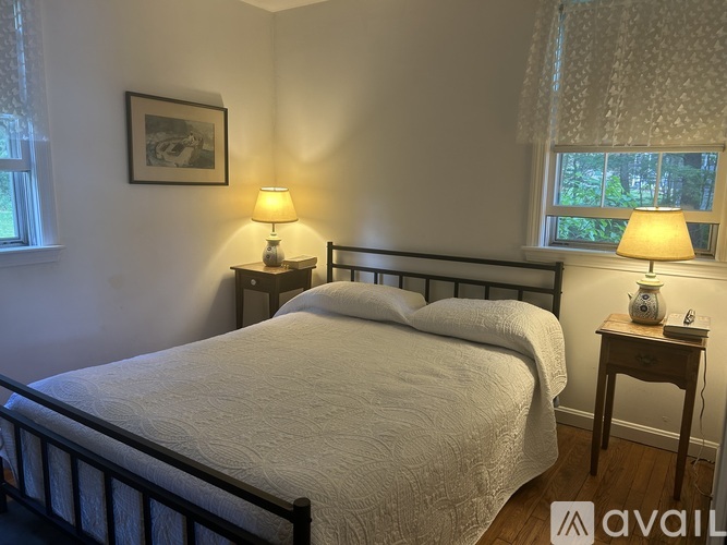 A bedroom with a bed, two nightstands with lamps, and a picture on the wall.