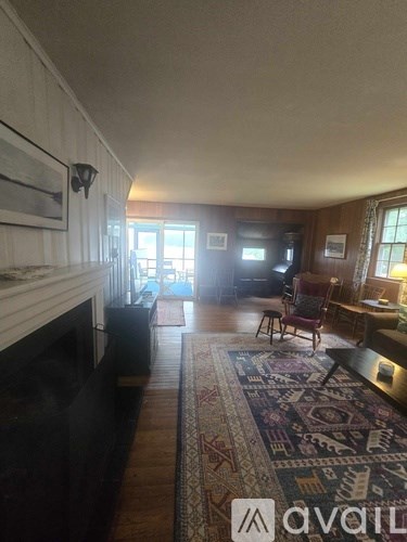 A living room with a rug and a fireplace.