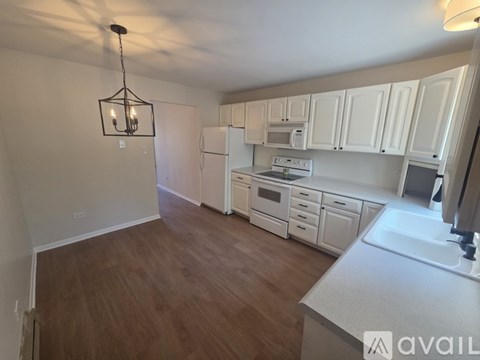A kitchen with white cabinets and a wooden floor.