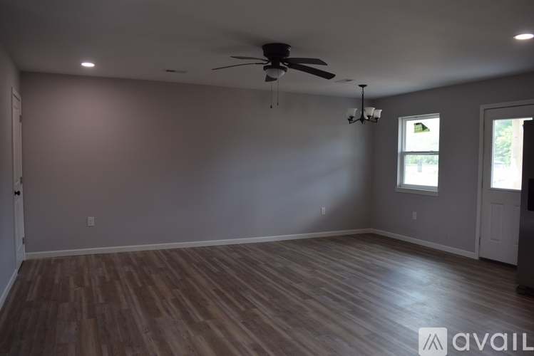 A spacious room with wooden flooring and a ceiling fan.