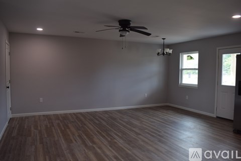 A spacious room with wooden flooring and a ceiling fan.