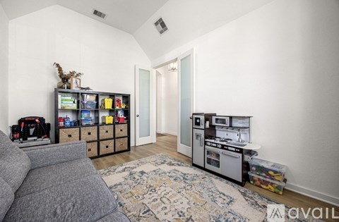 A living room with a grey couch and a rug on the floor.