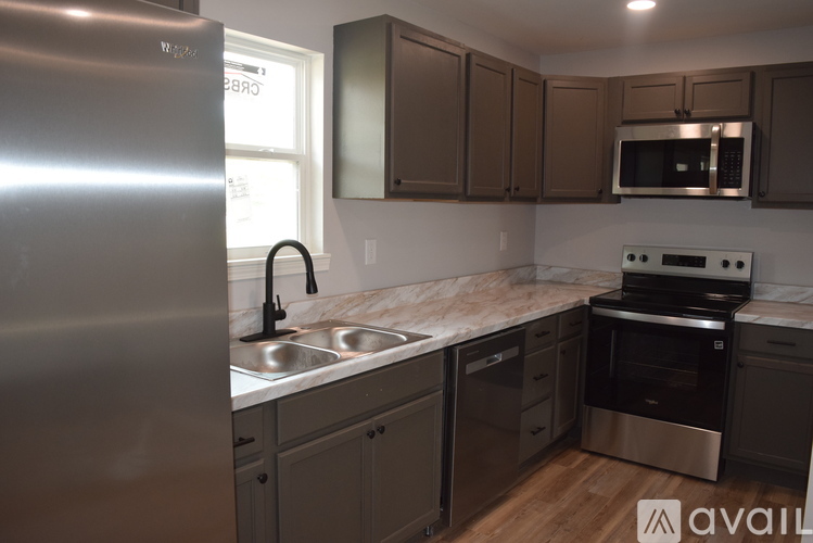 A kitchen with a stainless steel refrigerator and a marble countertop.
