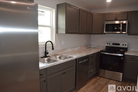 A kitchen with a stainless steel refrigerator and a marble countertop.