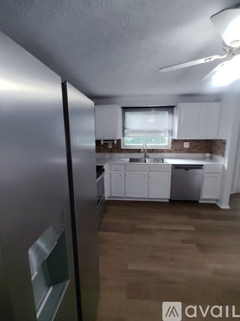 A kitchen with white cabinets and a stainless steel refrigerator.