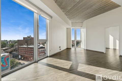 A spacious room with wooden floors and a view of the city through large windows.