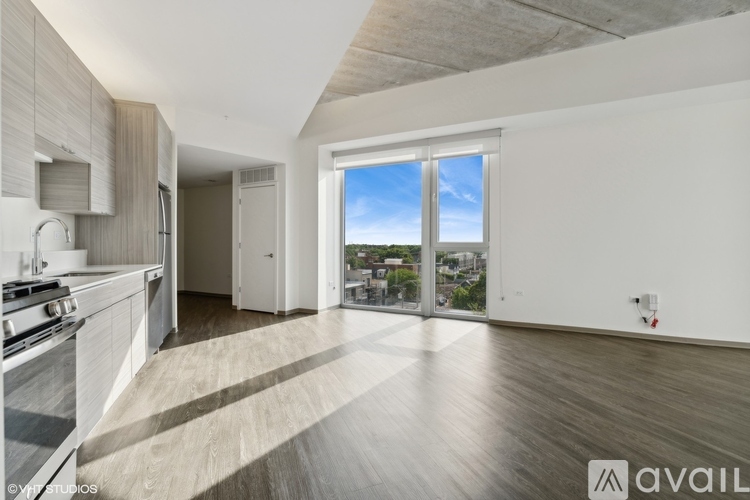 A spacious kitchen with wooden floors and a view of the city through the windows.