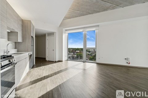 A spacious kitchen with wooden floors and a view of the city through the windows.