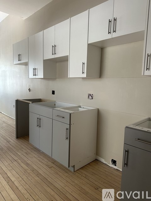 A kitchen with white cabinets and a wooden floor.