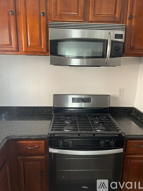 A kitchen with a black stove top oven and a microwave above it.