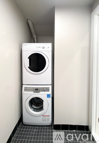 A white dryer and washer stacked on top of each other in a small room.