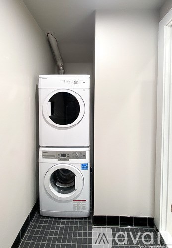 A white dryer and washer stacked on top of each other in a small room.