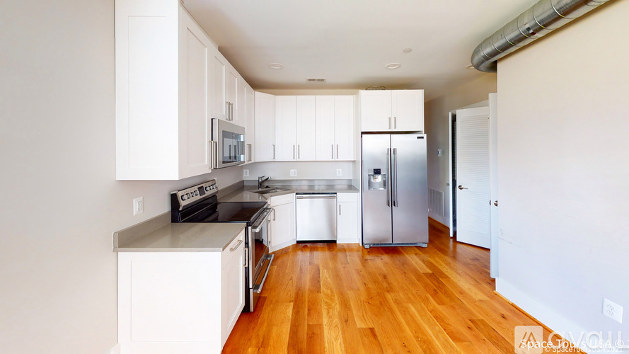 A kitchen with white cabinets and a wooden floor.