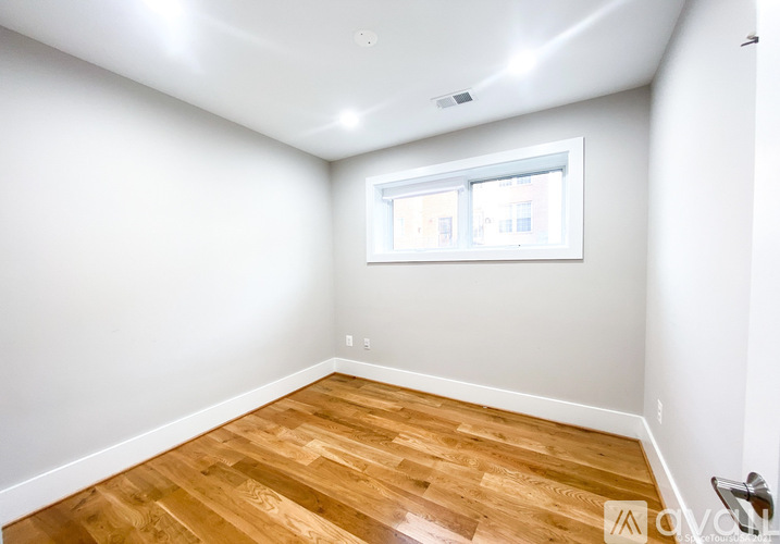 A room with wooden flooring and a window.