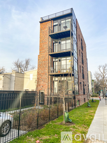 A modern brick building with balconies and a black fence in front.