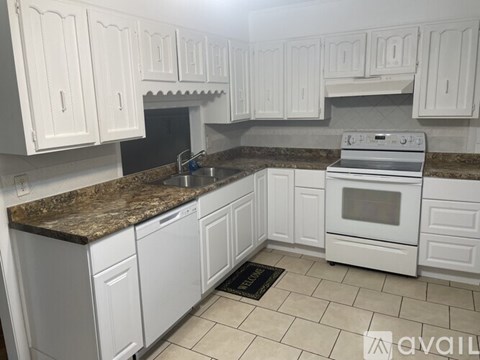 A kitchen with white cabinets and a granite countertop.