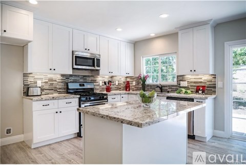 A kitchen with white cabinets and a granite countertop.