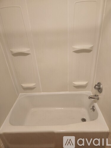 A white bathroom with a tub and towel racks.