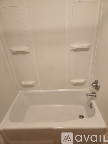 A white bathroom with a tub and towel racks.