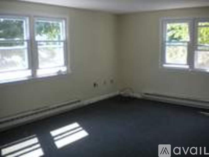 A room with two windows and a wall that is painted white.