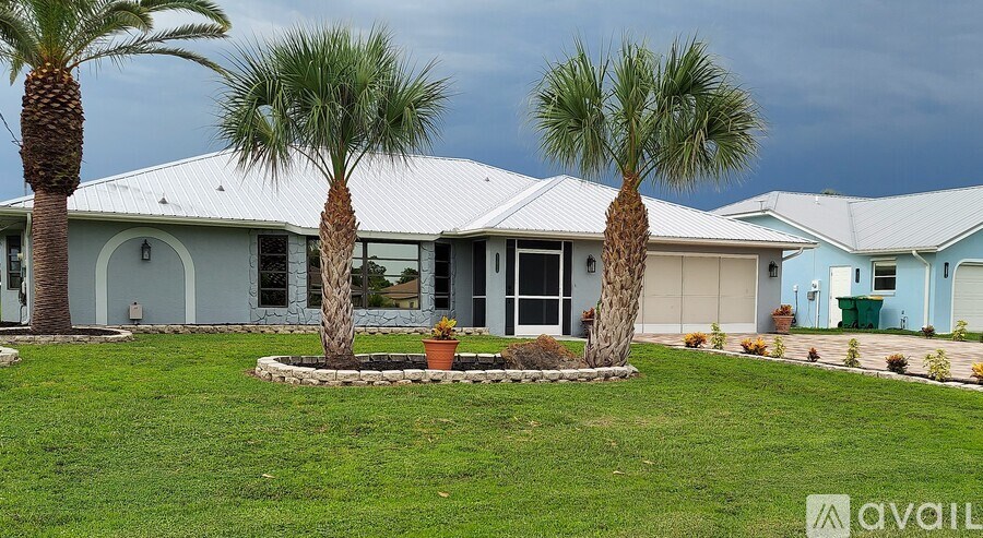A house with a white roof and a palm tree in front.
