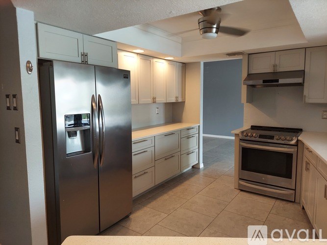 A kitchen with a stainless steel refrigerator and a stove top oven.