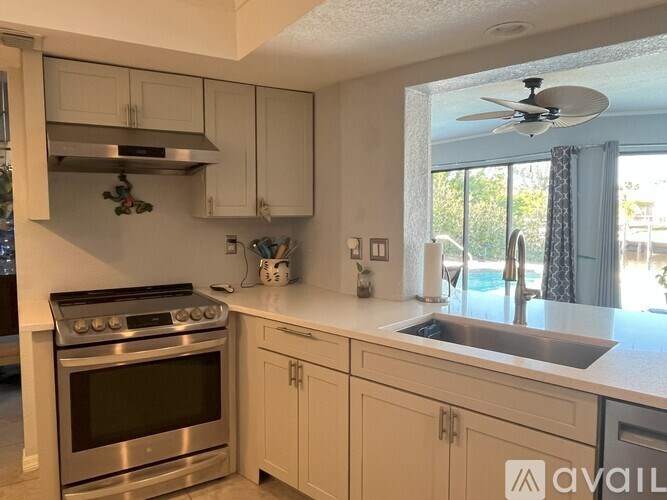A kitchen with a stove, sink, and cabinets.