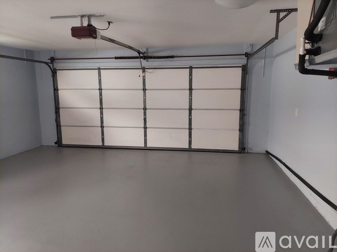A spacious garage with a white door and a grey floor.