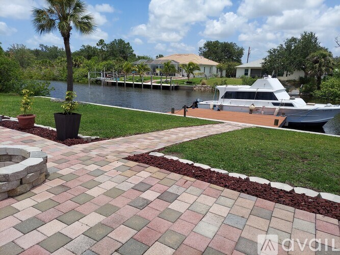 A brick walkway leads to a boat docked at a marina.