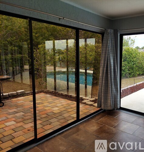 A glass door with a curtain leading to a pool.
