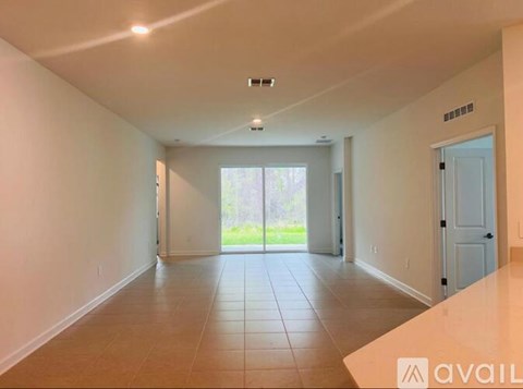 A spacious room with tiled flooring and a sliding glass door leading to a garden.
