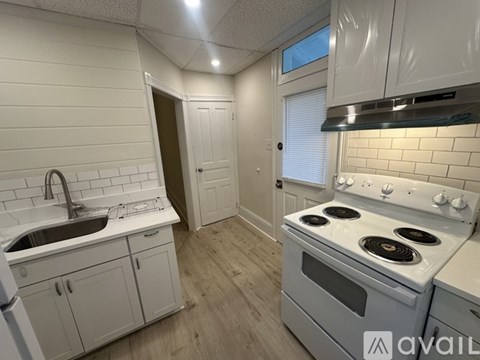 A kitchen with white cabinets and a stove top oven.