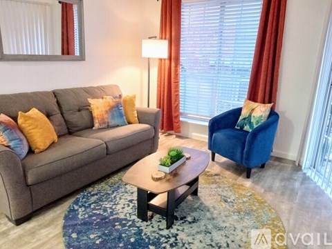 A living room with a grey couch, a blue armchair, and a coffee table with a plant on it.