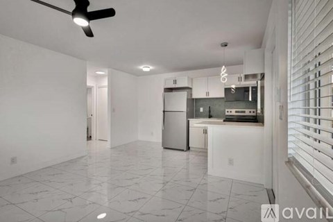 A spacious kitchen with white cabinets and a black ceiling fan.