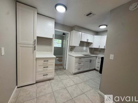 A kitchen with white cabinets and a tiled floor.